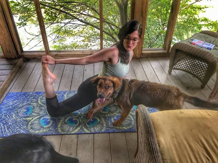 Reviewer flexes foot on peacock-print yoga mat indoors