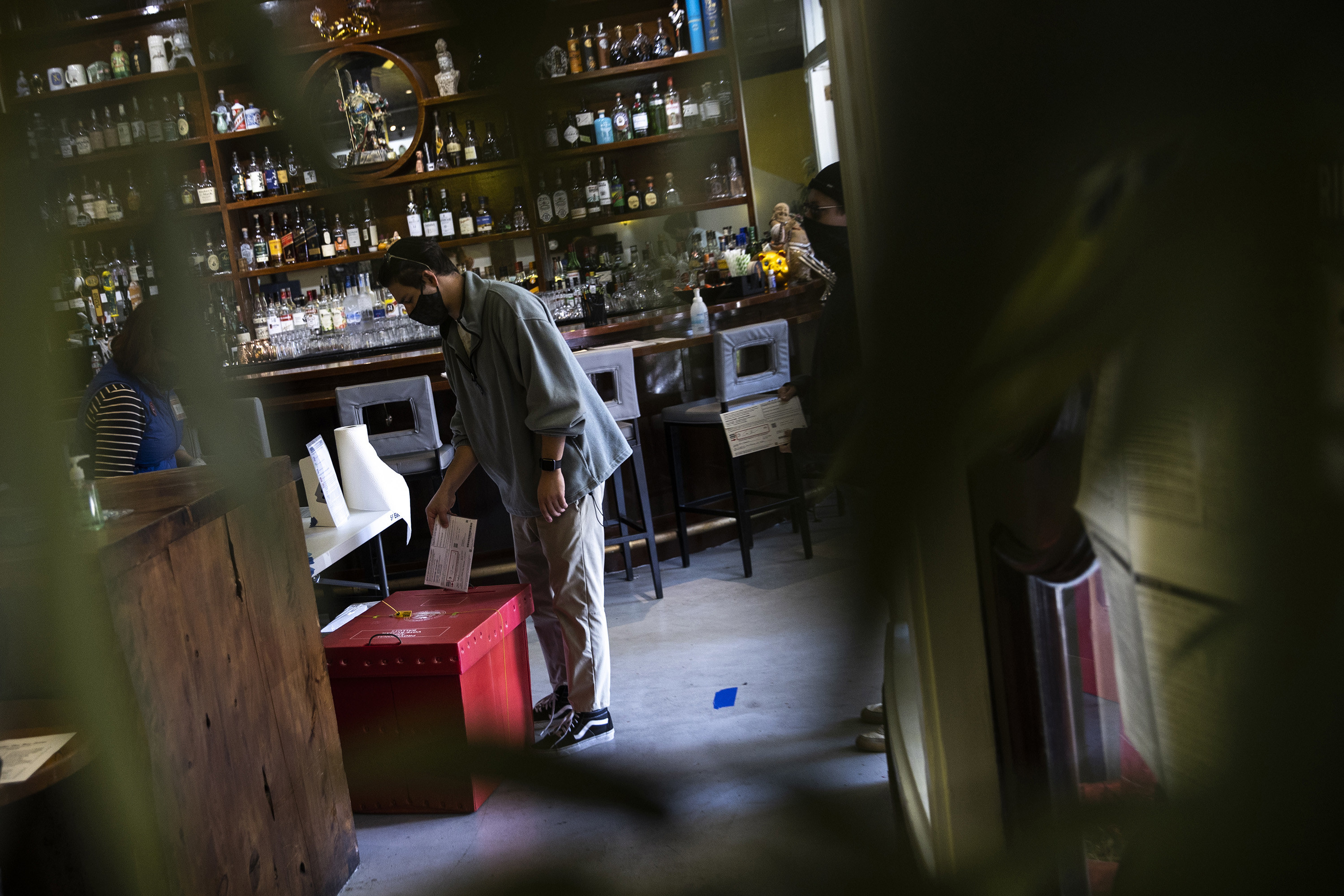 Man dropping ballot in red box at a restaurant. 