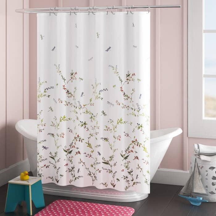 a white shower curtain with flowers and dragonflies drawn throughout