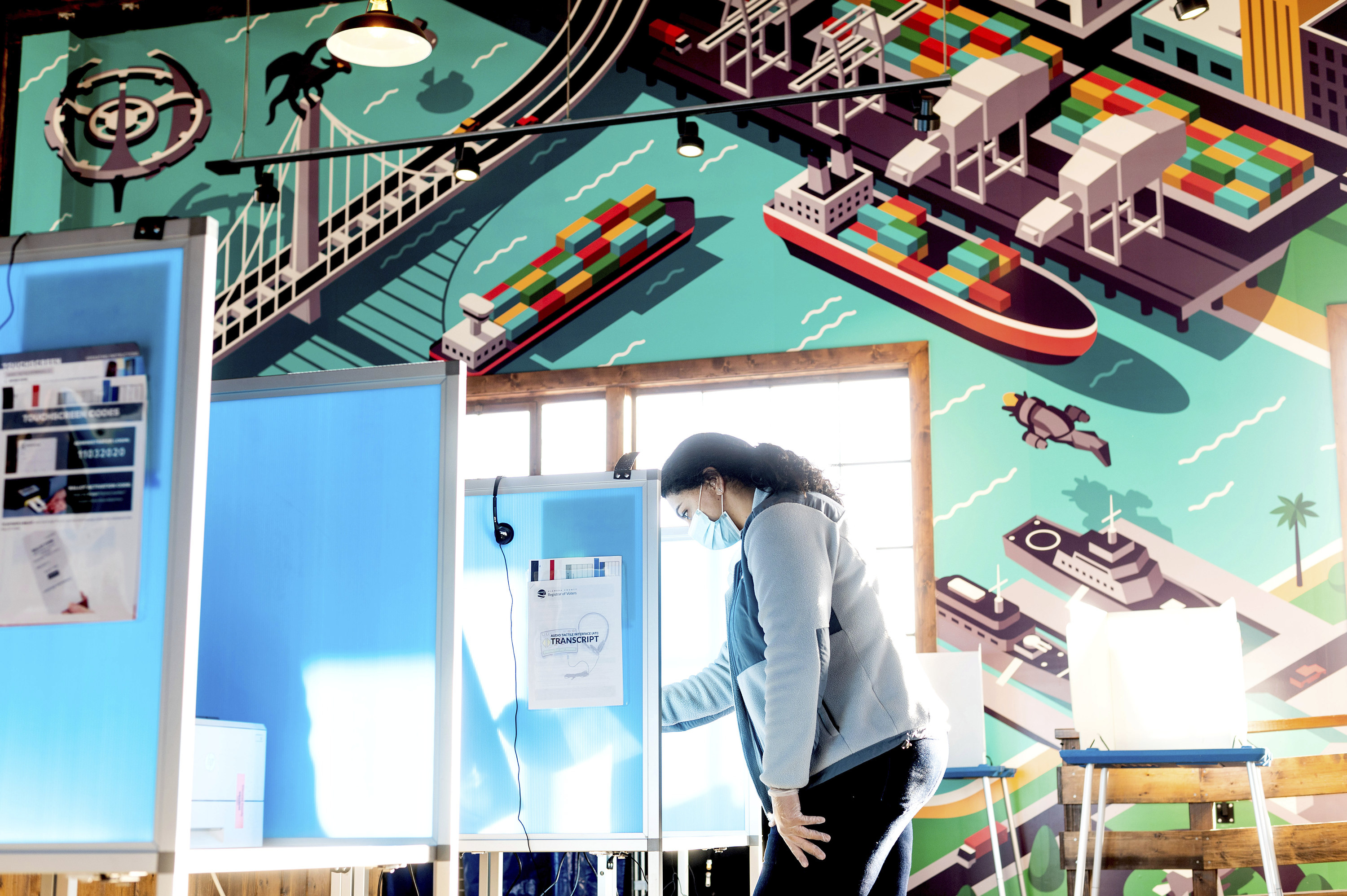 Woman voting under a mural.