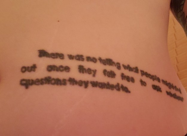 A tattoo of a quote from Catch-22 in a plain black font on someone&#x27;s stomach