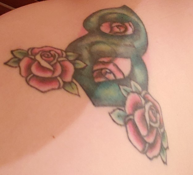 A tattoo of the number eight with pointed ends on each side with pink roses around it