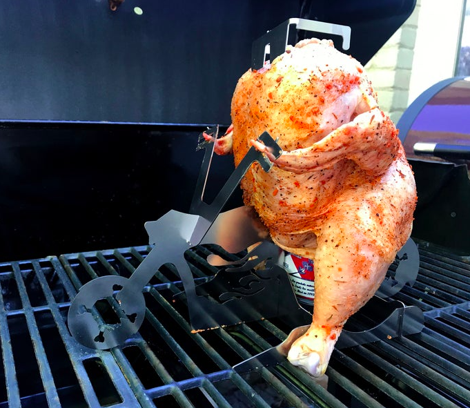 a whole raw chicken riding what looks like a motorcycle on a bbq