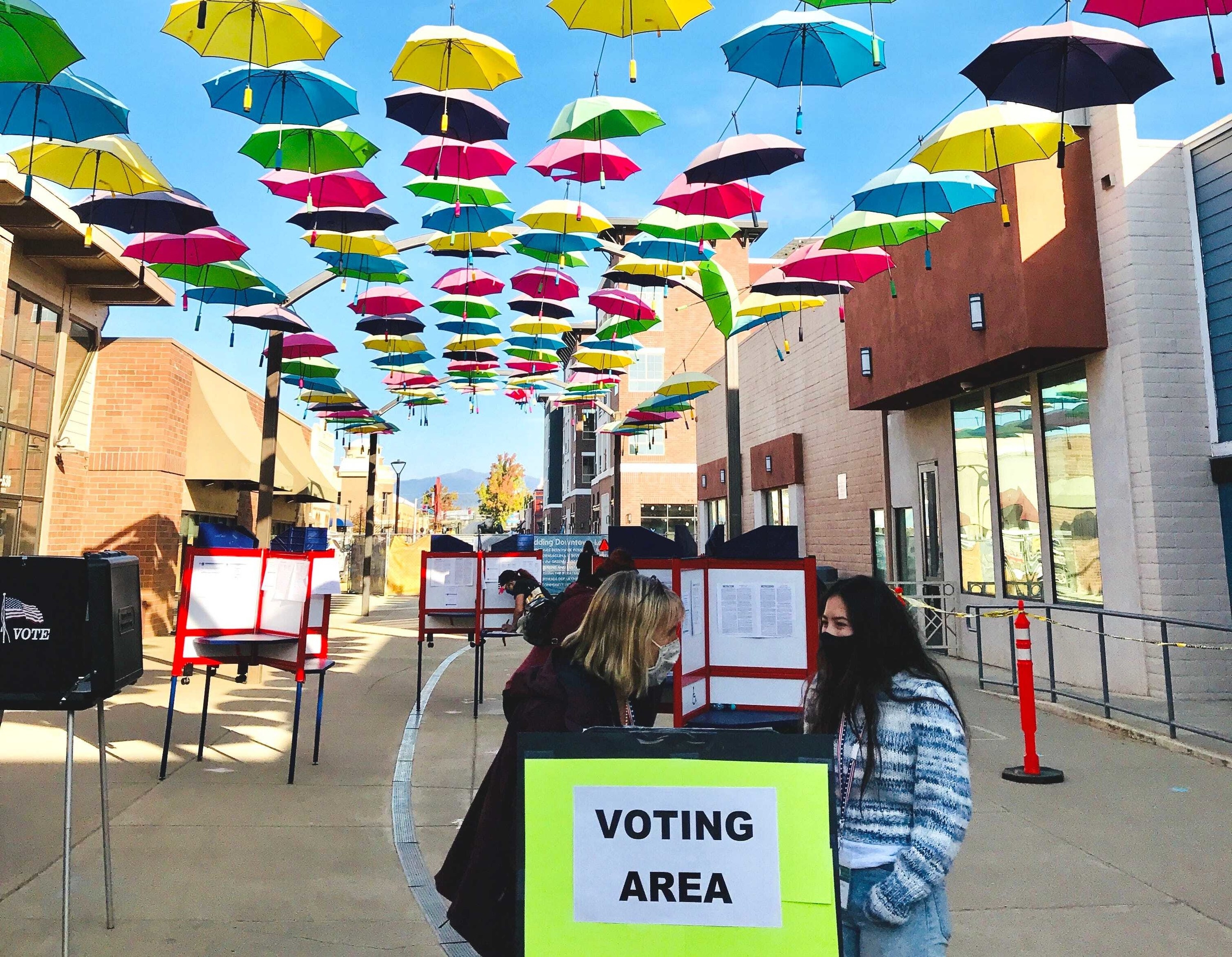 Two women and ballot boxes under umbrellas 