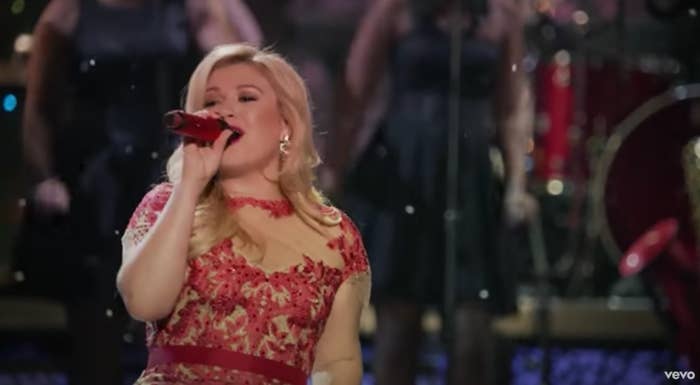 Kelly Clarkson singing in a formal red dress as snow falls around her
