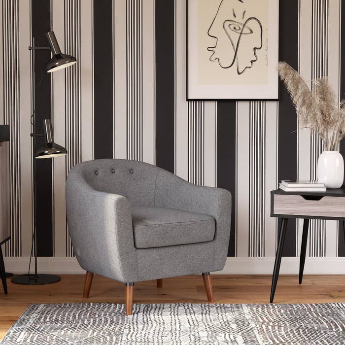 grey barrel-style chair with wooden legs and tufted accents