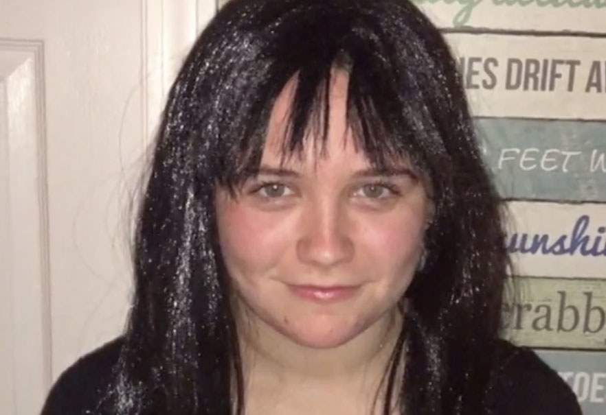 A woman wears a black wig