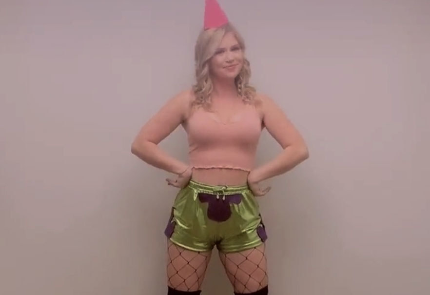 A woman dressed in green shorts, a pink top and fishnet stockings