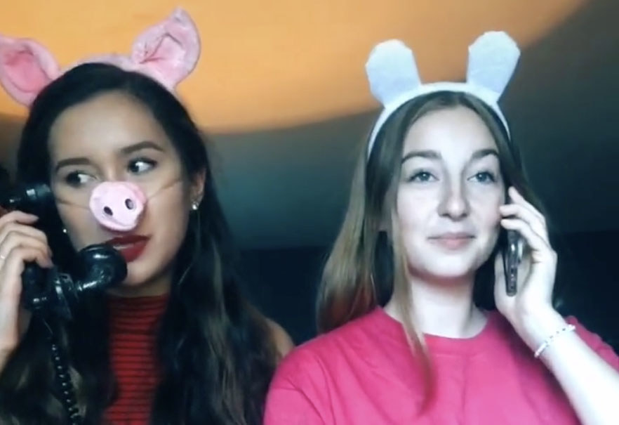 A woman dressed as Peppa Pig and her friend chat on their phones