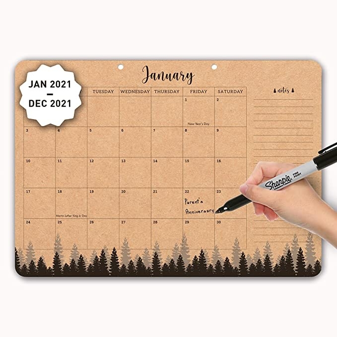 Brown wall calendar with a forest print at the bottom.