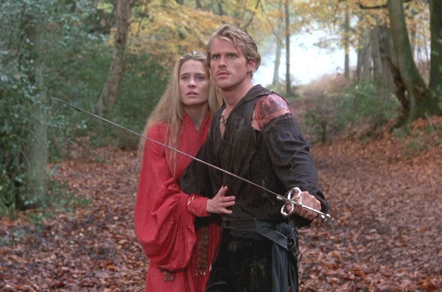 Westley and Buttercup in the forest; Westley has his sword drawn, while protecting Buttercup