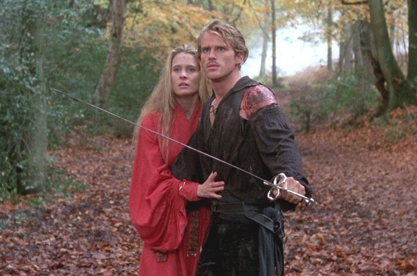 Westley and Buttercup in the forest; Westley has his sword drawn, while protecting Buttercup