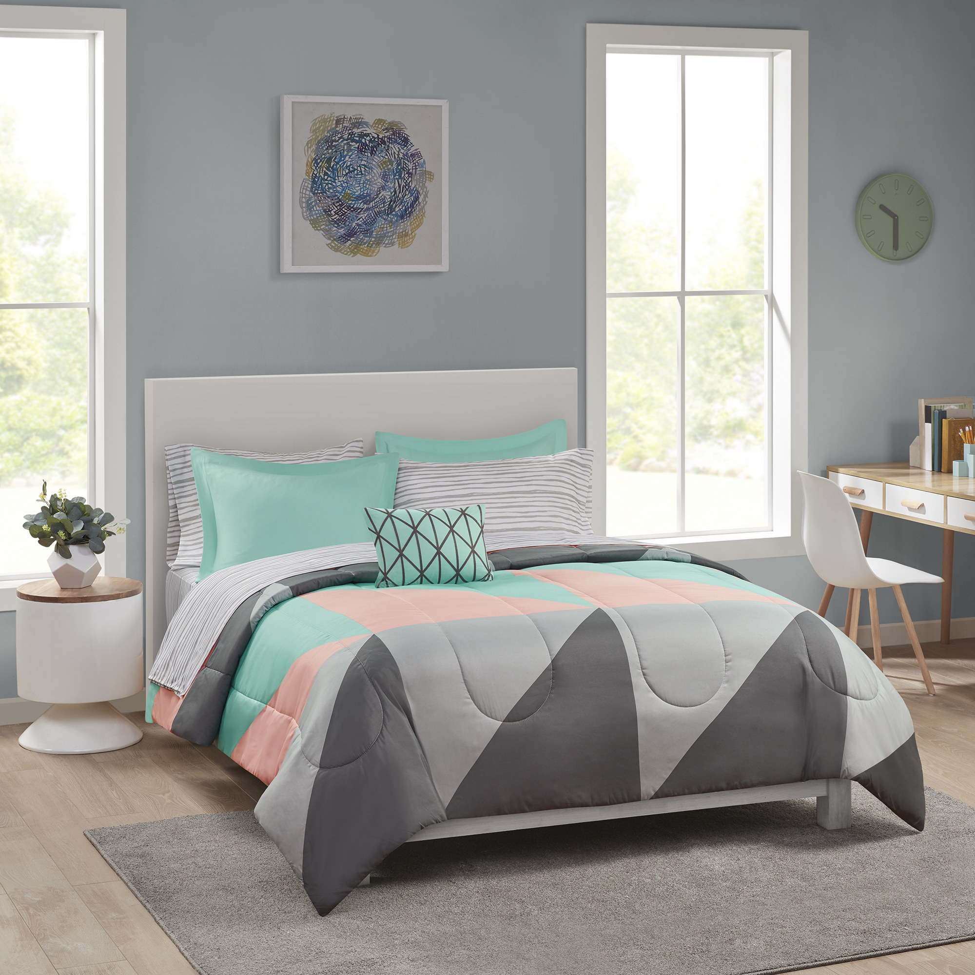 grey pink and teal comforter and bedding set on a bed in a bedroom