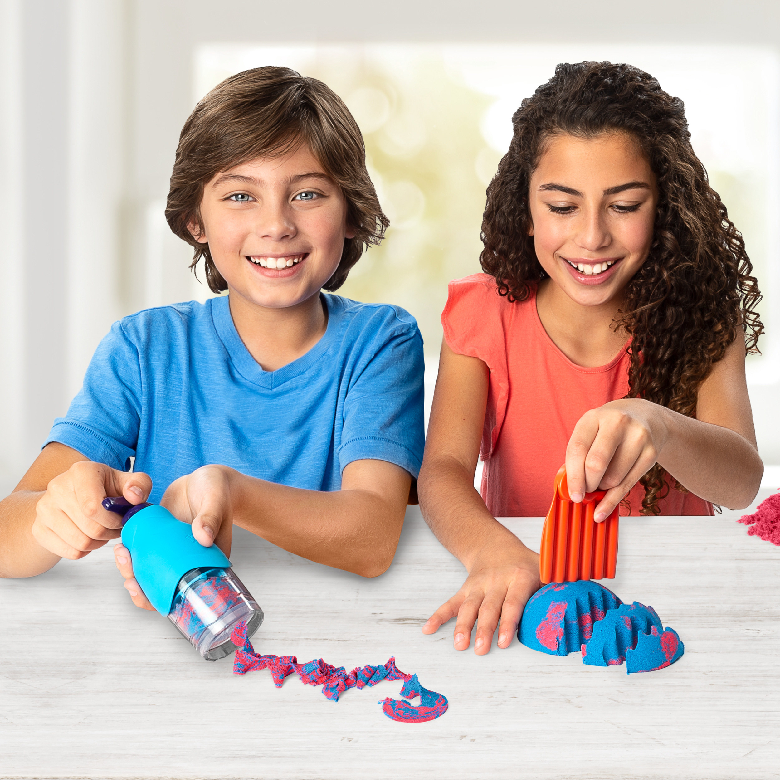 two kids playing with a kinetic sand kit