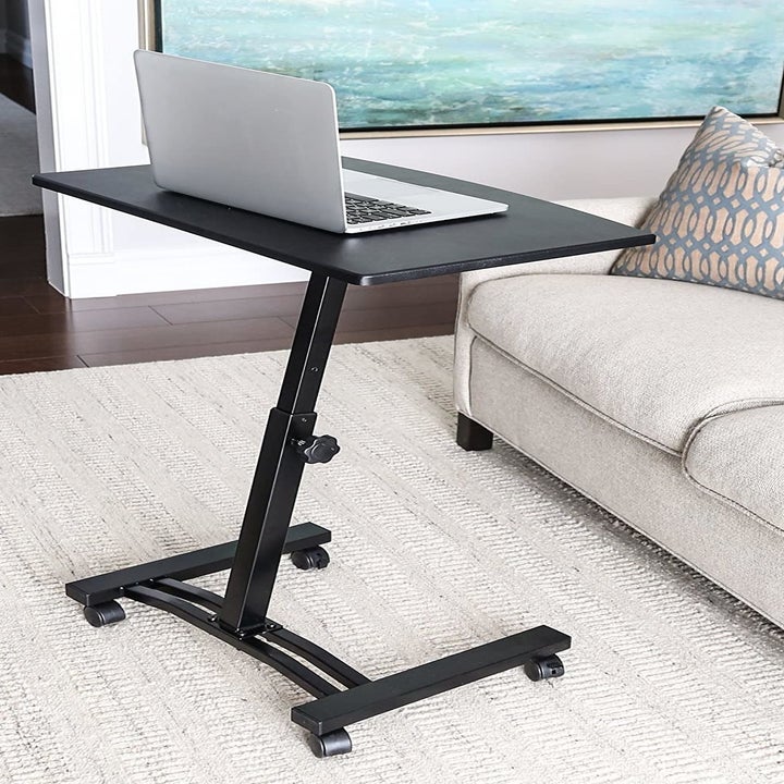 Flat-top laptop cart with wheels sitting in a living room in front of a couch 