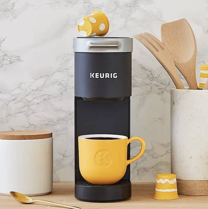 keurig on a table with a yellow mug full of coffee