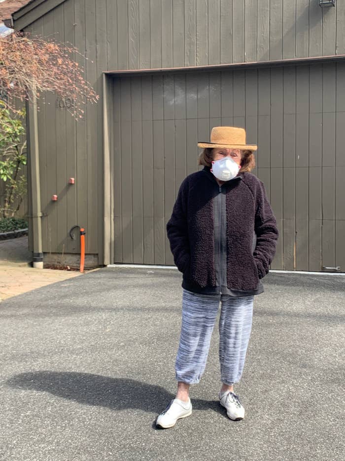 My grandma wearing a mask standing outside her house.