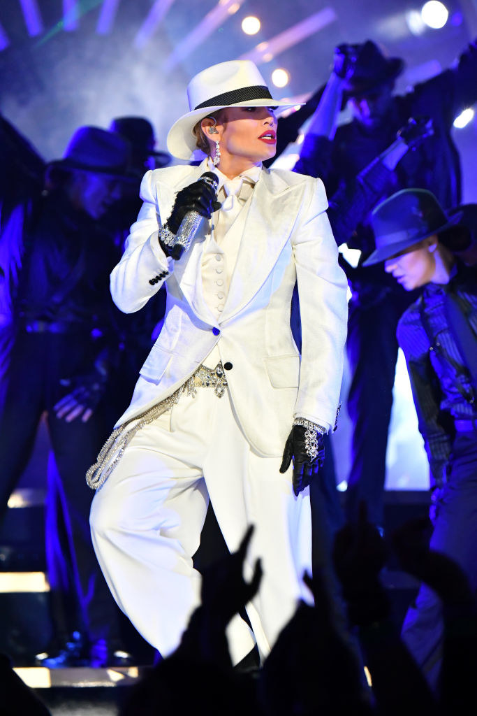 white 3-piece suit with a tie and vest underneath with a rhinestone belt and cuffs and loose pants