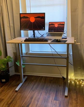 Reviewer photo of the raised desk supporting a monitor, a laptop, and a keyboard 