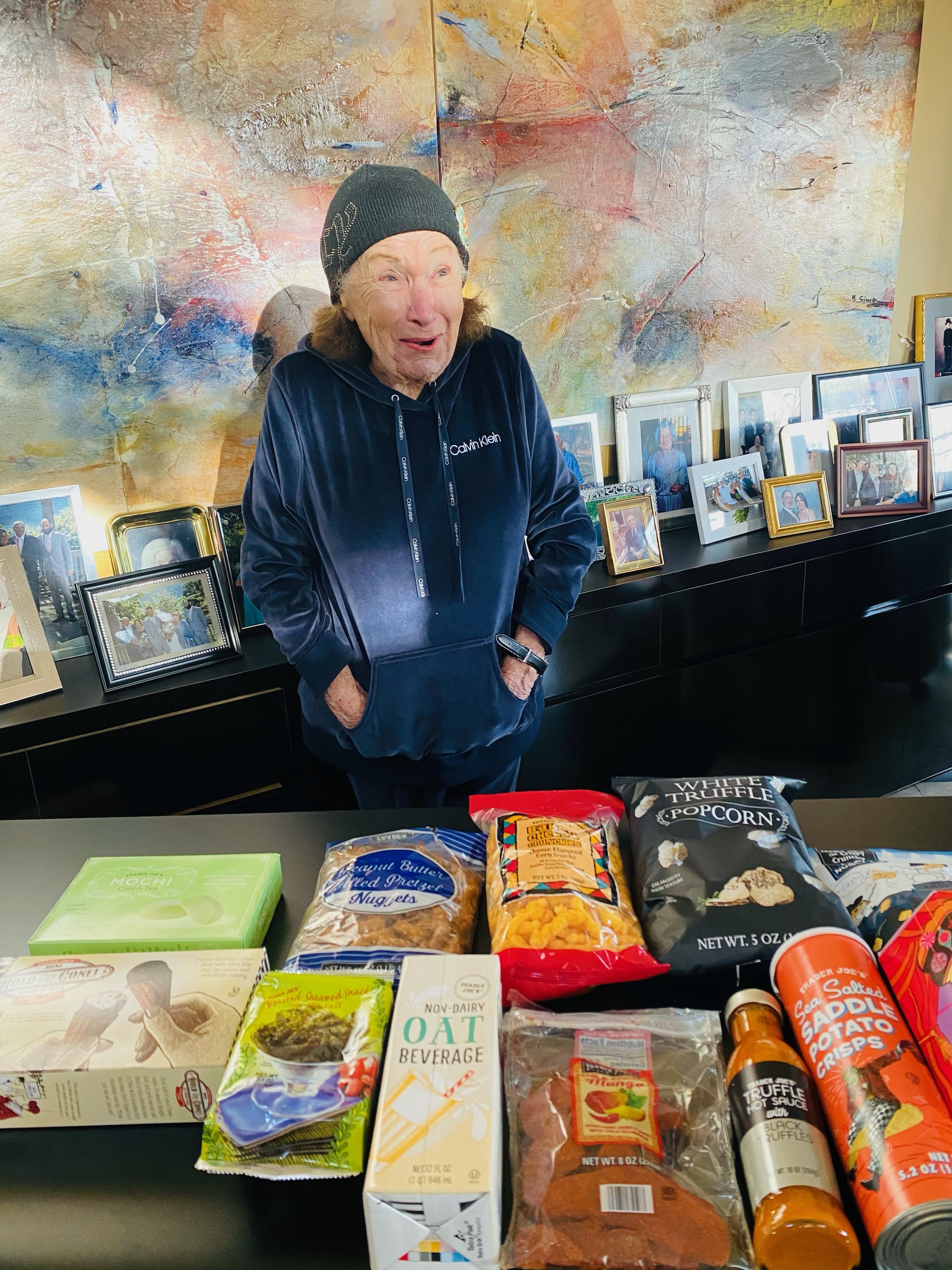 My grandma standing with a countertop full of Trader Joe&#x27;s snacks.