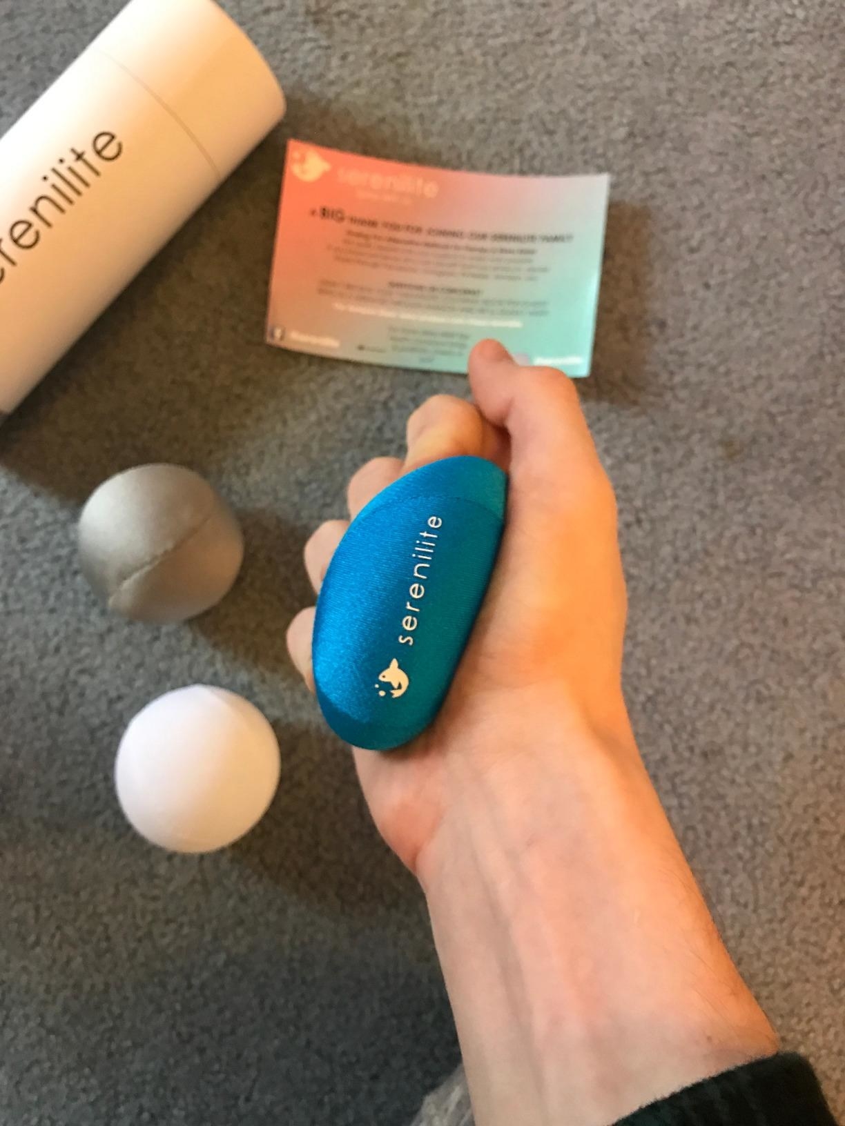 reviewer image of a hand squeezing one of the serenilite hand therapy balls