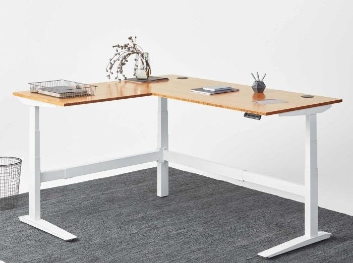 一个l型的桌子birchwood最高,白腿,和一个小的控制面板调整高度