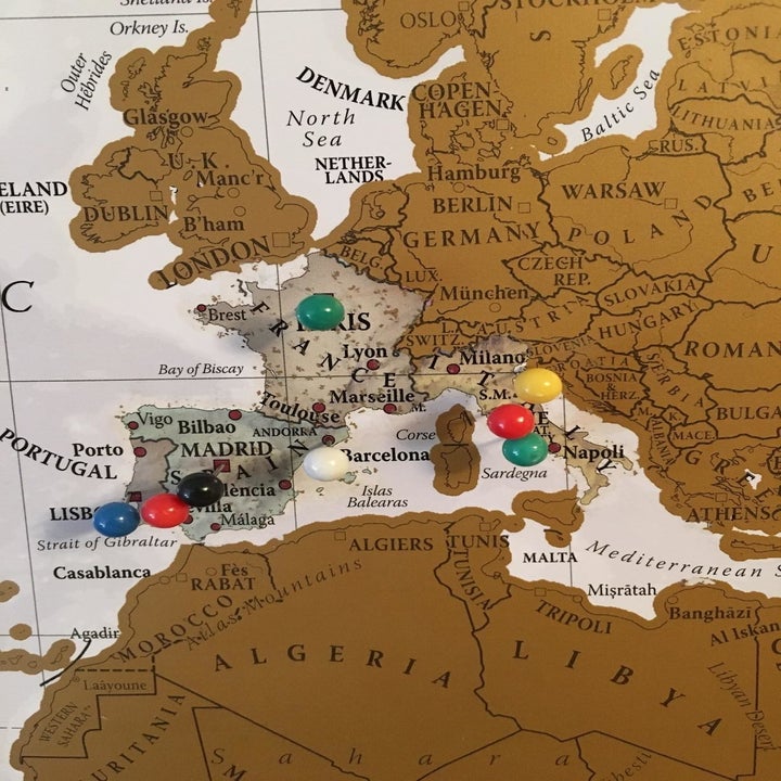 A closeup of the map with some European countries scratched off and drawing pins stuck in certain cities