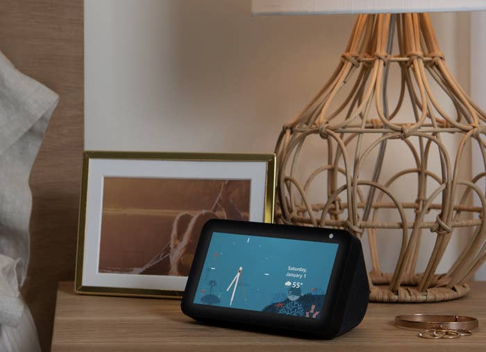 the amazon echo show 5 displaying the date and weather on a nightstand