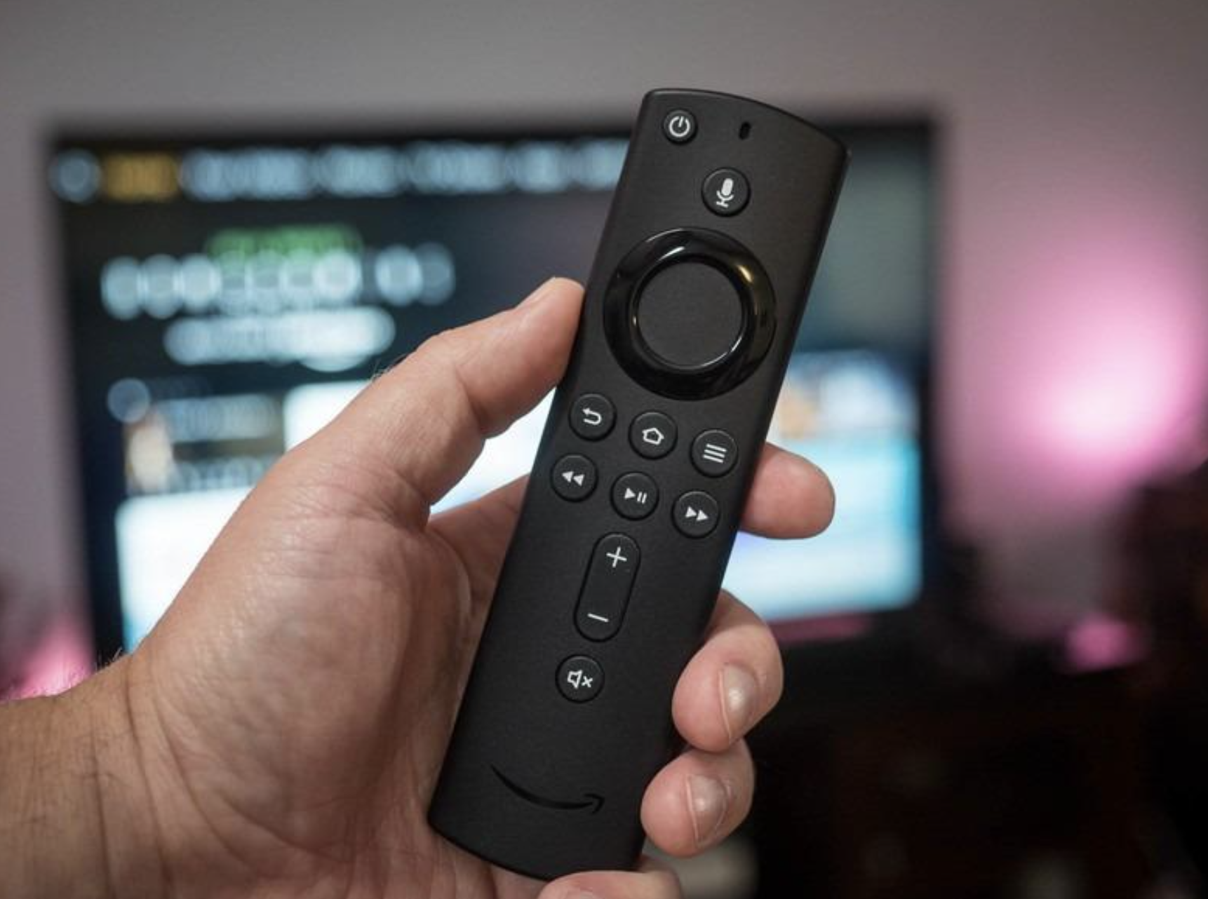 reviewer holding fire stick with tv screen in background