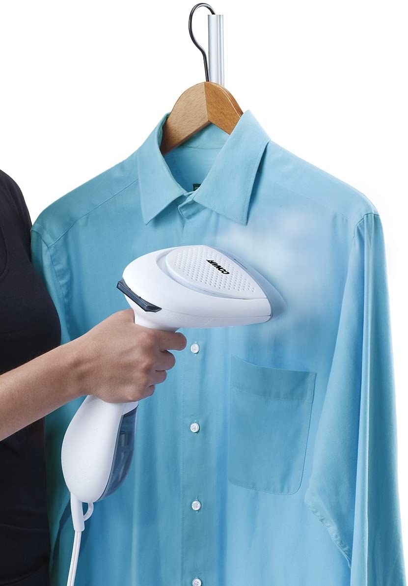 A person uses the steamer to eliminate wrinkles on a dress shirt