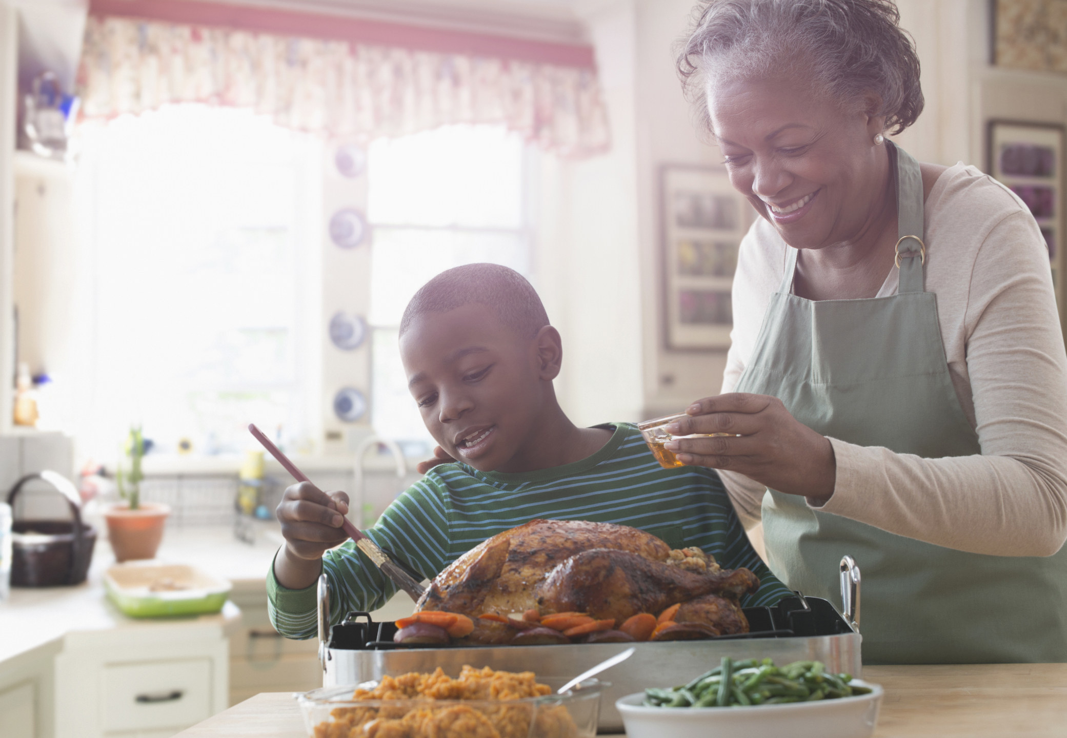 A grandmother and her grandson cook a turkey together 