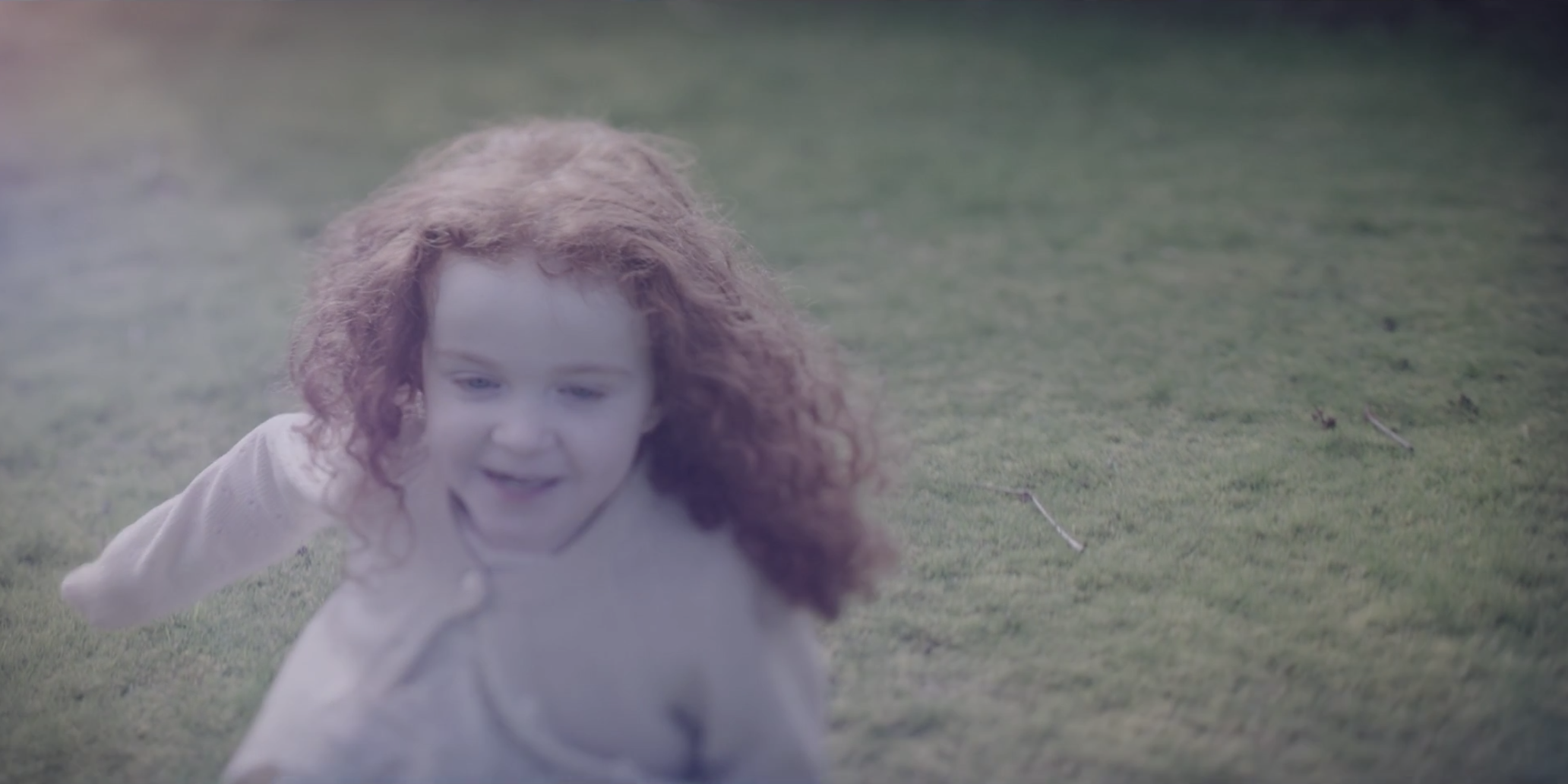 A little girl with curly red hair playing.