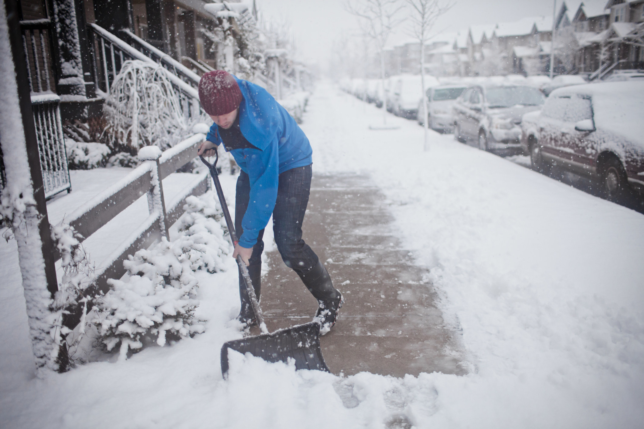 A man shovels snow on the sidewalk 