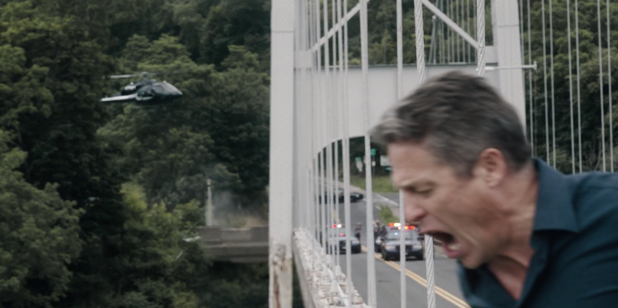 Jonathan about to jump off the bridge with the helicopter in the background.