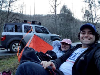 Two reviewers sitting in hammock attached to a car