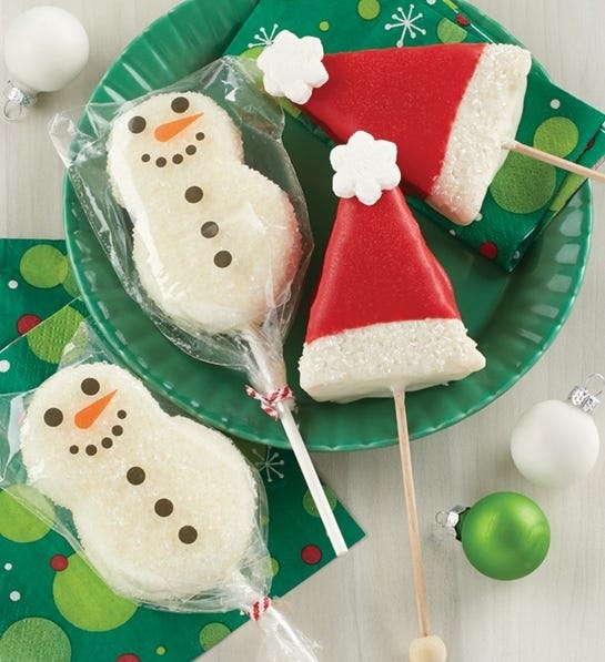 Two snowman and two Santa hat desserts on popsicle sticks 