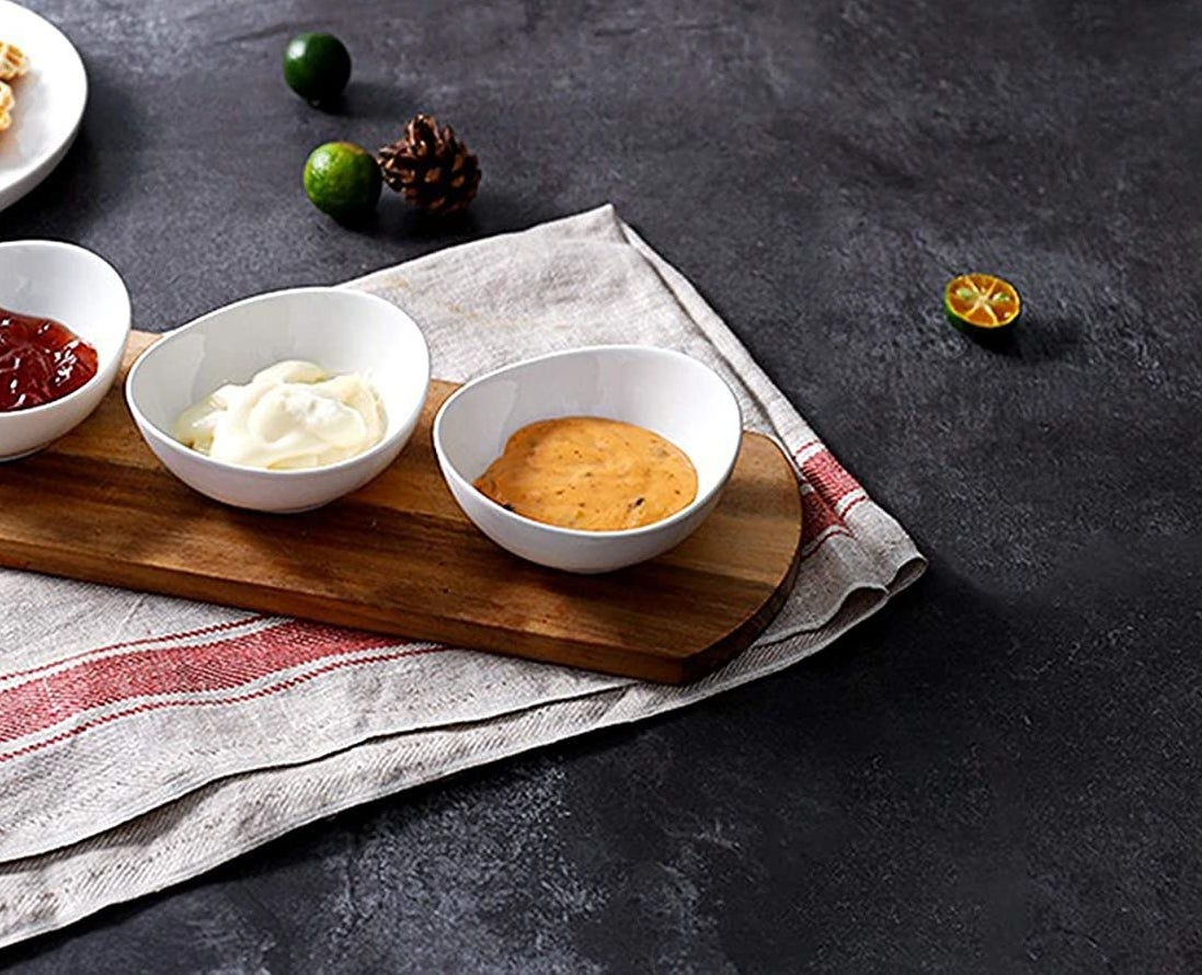 Set of white porcelain bowls with dips on a table
