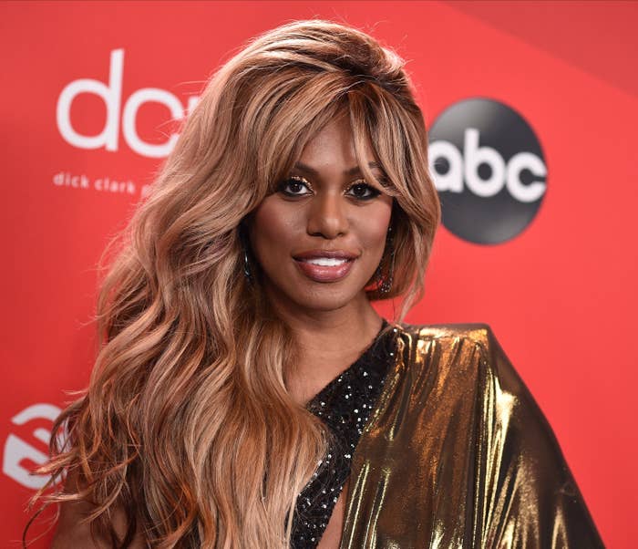 Laverne Cox wears a gold dress on a red carpet for the 2020 American Music Awards