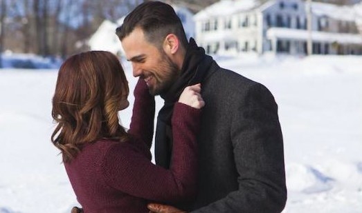 Still from The Spirit of Christmas: Jen Lilley and Thomas Beaudoin embrace in front of a snow-covered lawn