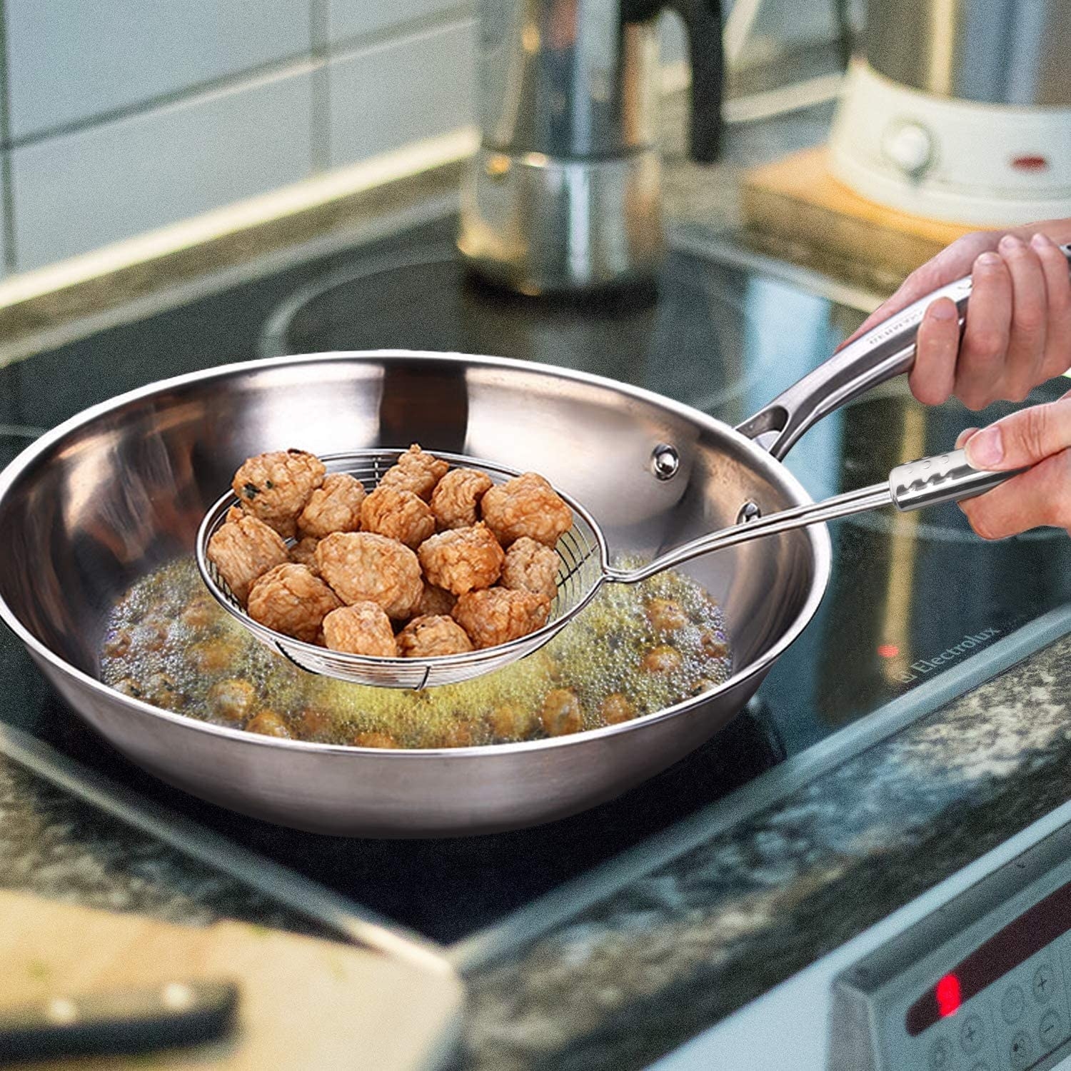 A person strains food from a pan of oil