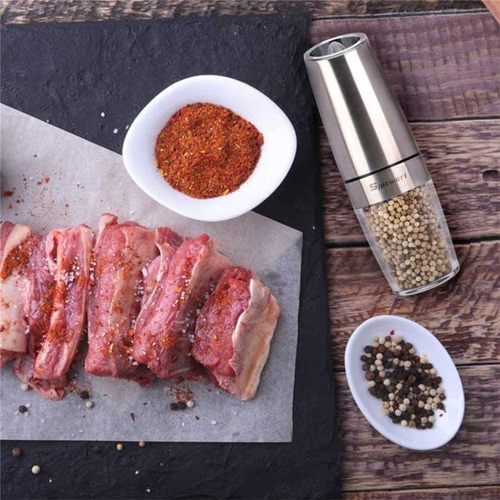 A pepper mill beside meat and spices