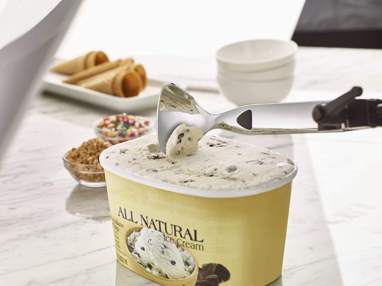 An ice cream scoop scoops up ice cream