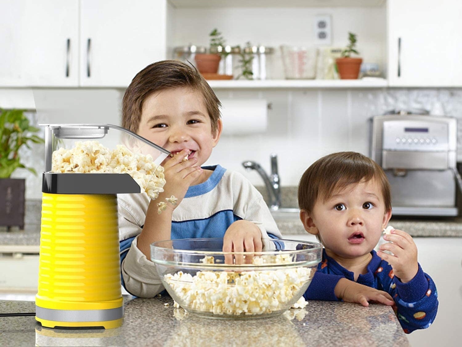 Two kids eat popcorn fresh from a popcorn maker