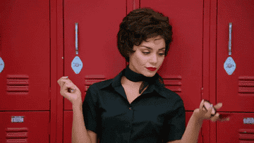 GIF of Vanessa Hudgens in Grease Live looking at herself in a compact mirror 