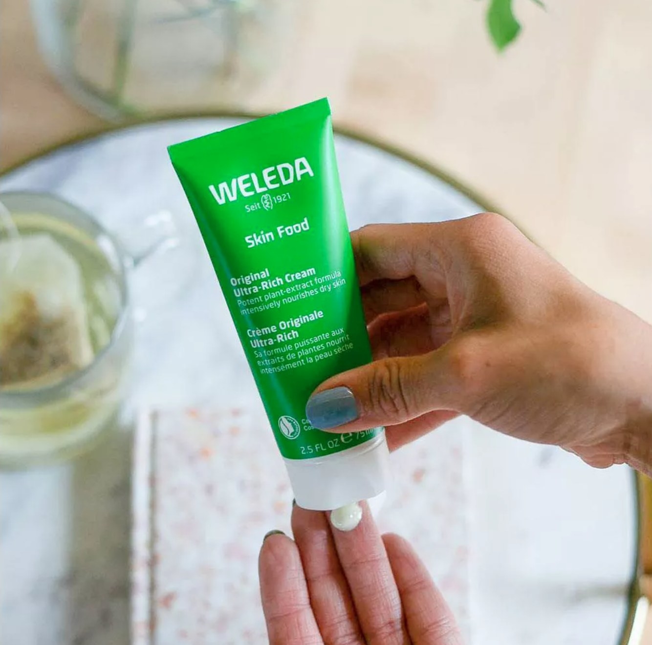hand squeezing a drop of weleda skin food