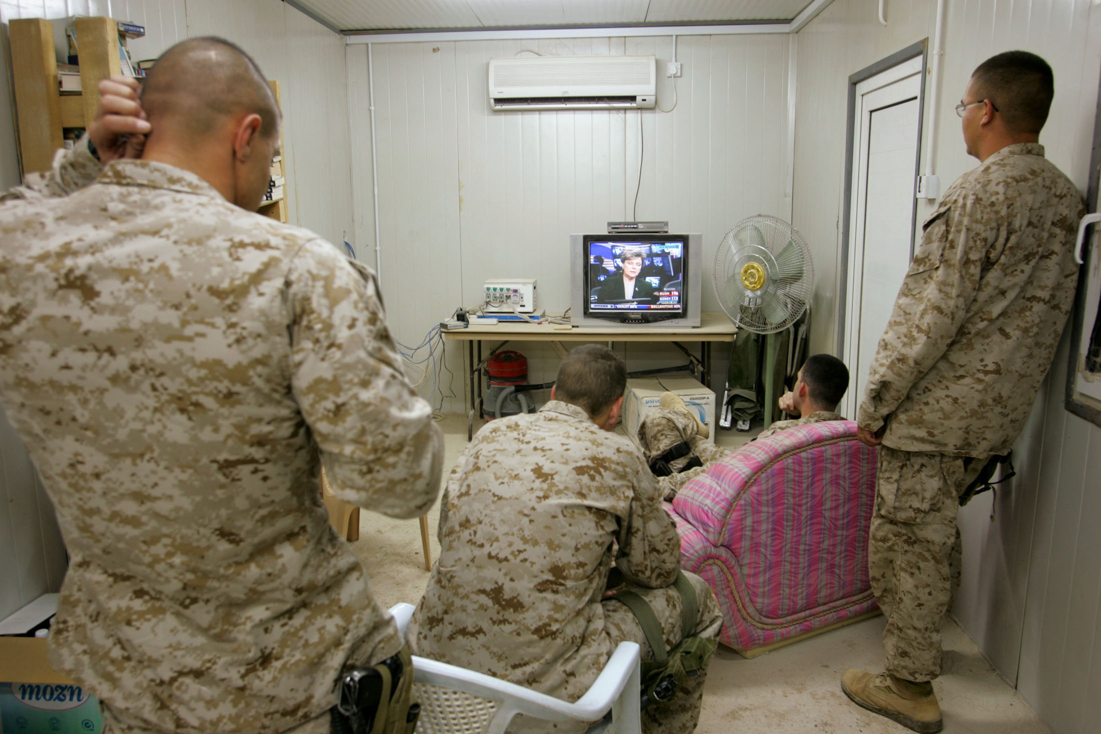 Men in camouflage watching a television with election results