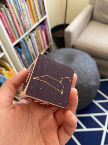 Reviewer's hand holding one of the blocks featuring a constellation 