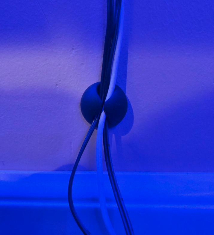 reviewer photo showing one of the cable clips attached to their wall with three cords being supported by it 