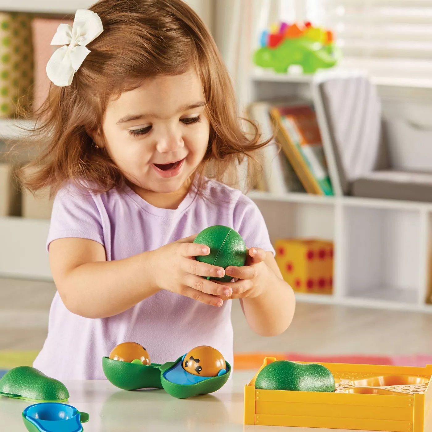 Child model playing with green plastic avocado