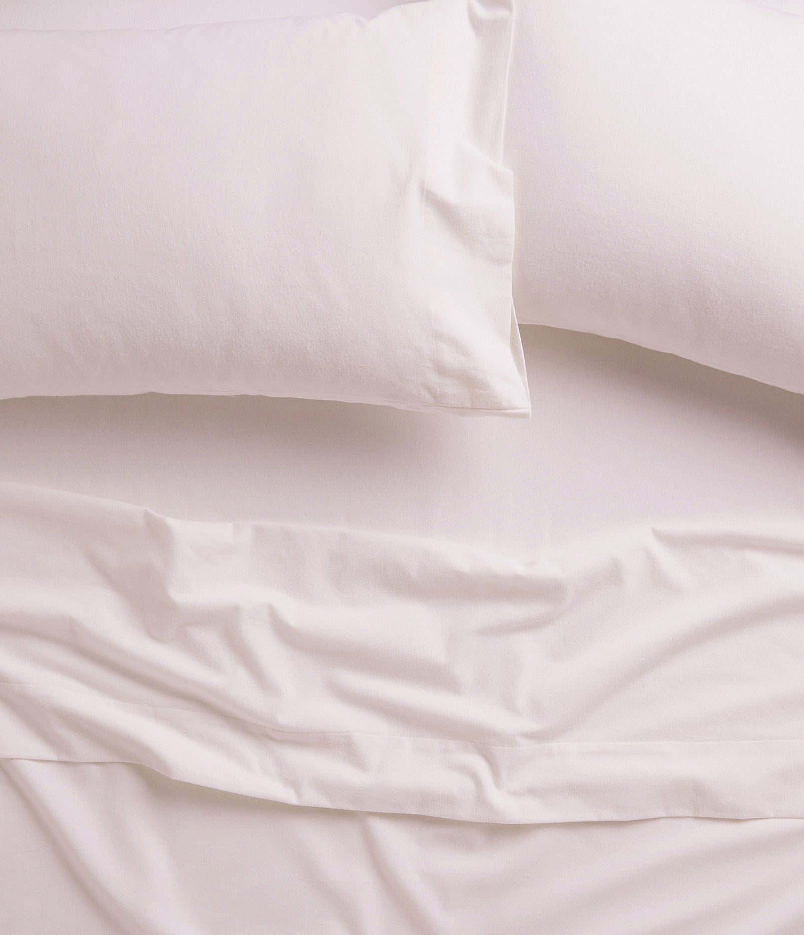 A bed covered with soft flannel sheets and two pillows